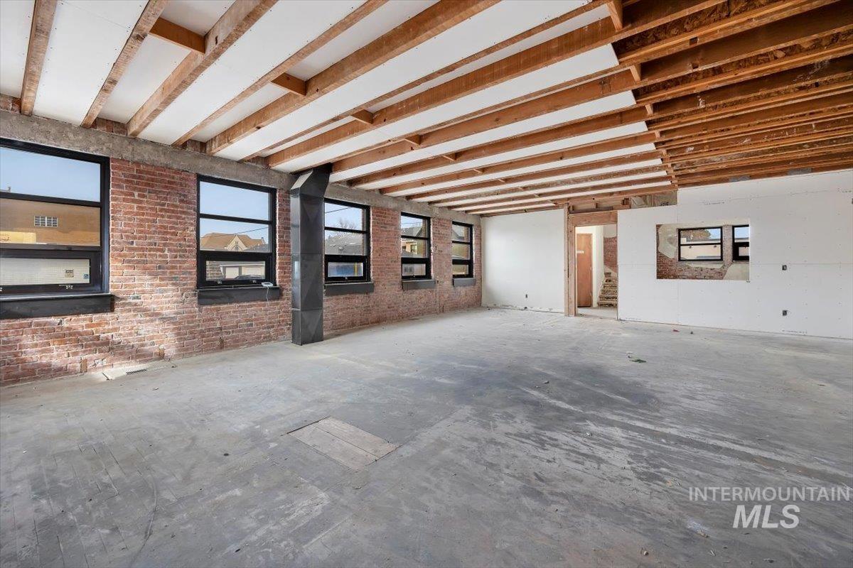 Unfurnished living room featuring brick wall
