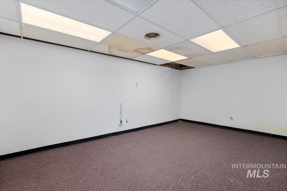 Carpeted empty room featuring a drop ceiling