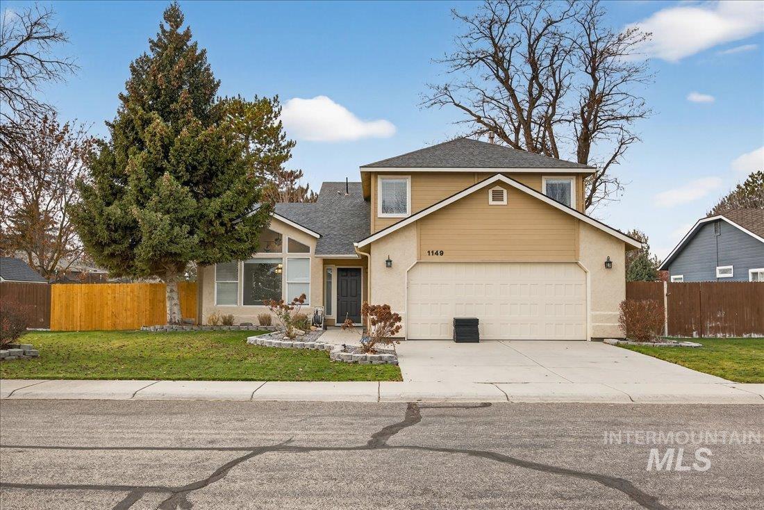 Traditional-style home featuring concrete driveway, a shingled roof, and an attached garage