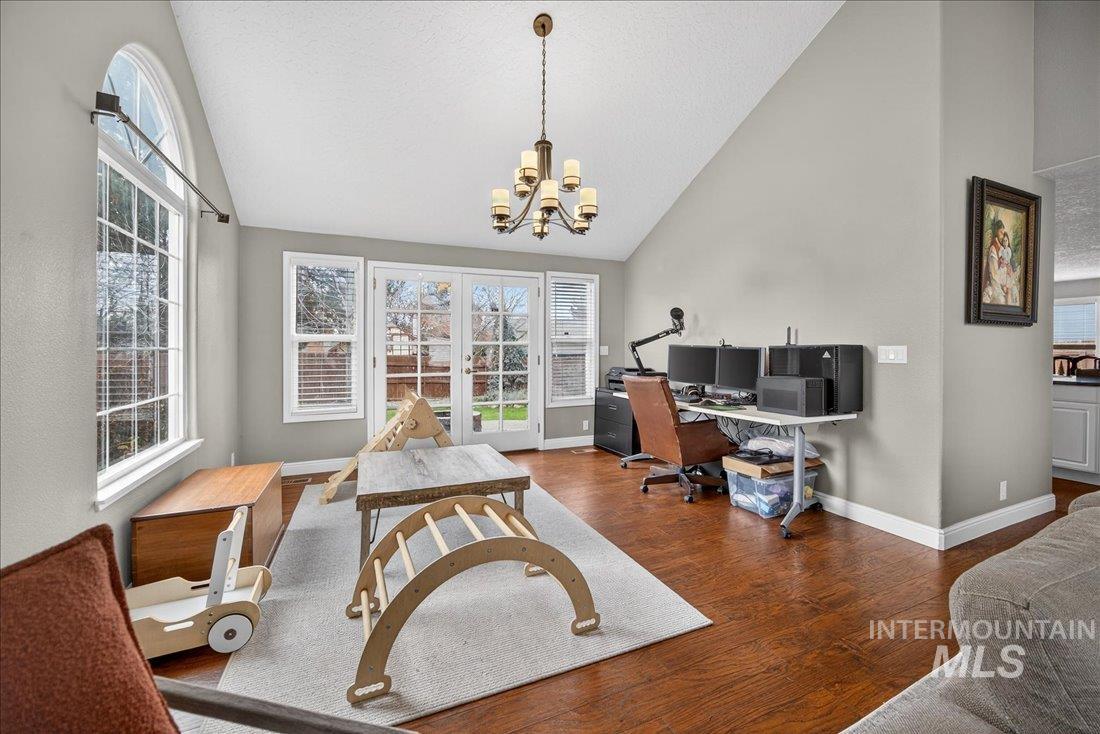Office space with dark wood-type flooring, healthy amount of natural light, a chandelier, high vaulted ceiling, and a textured ceiling