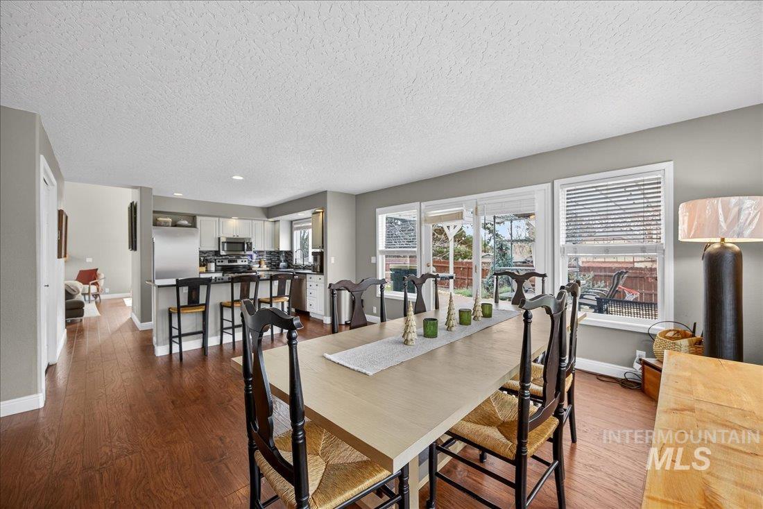 Dining area with a textured ceiling, dark wood-type flooring, and recessed lighting