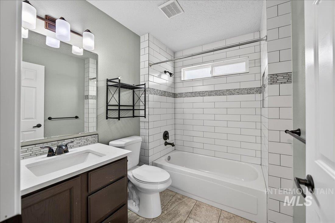 Bathroom featuring shower / washtub combination, vanity, and a textured ceiling