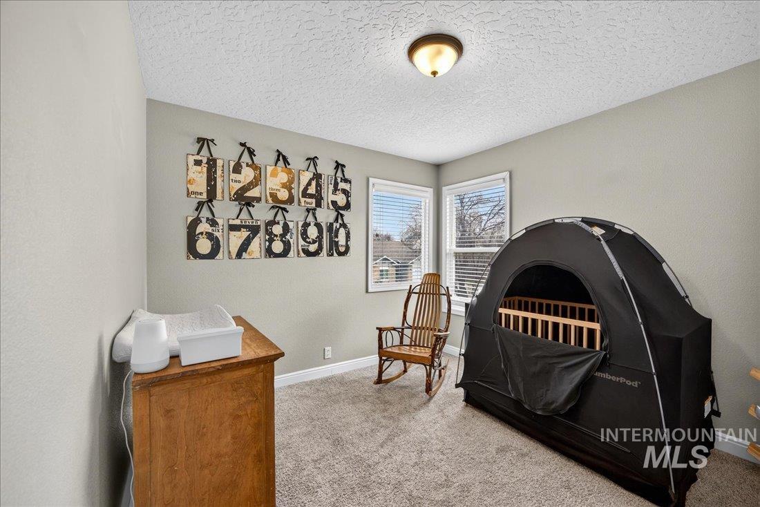 Carpeted bedroom featuring a textured ceiling and baseboards