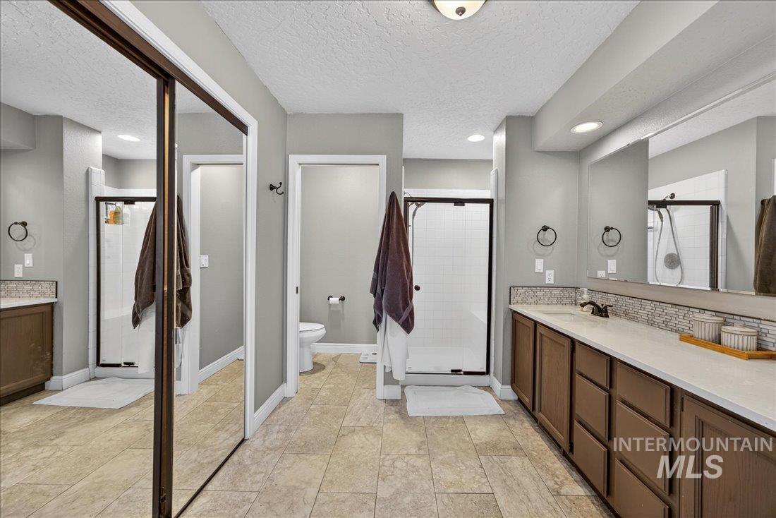 Bathroom with vanity, a textured ceiling, a shower stall, and recessed lighting