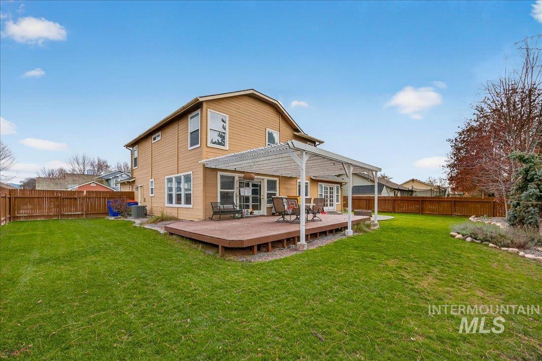 Back of property featuring a fenced backyard, a wooden deck, and a pergola