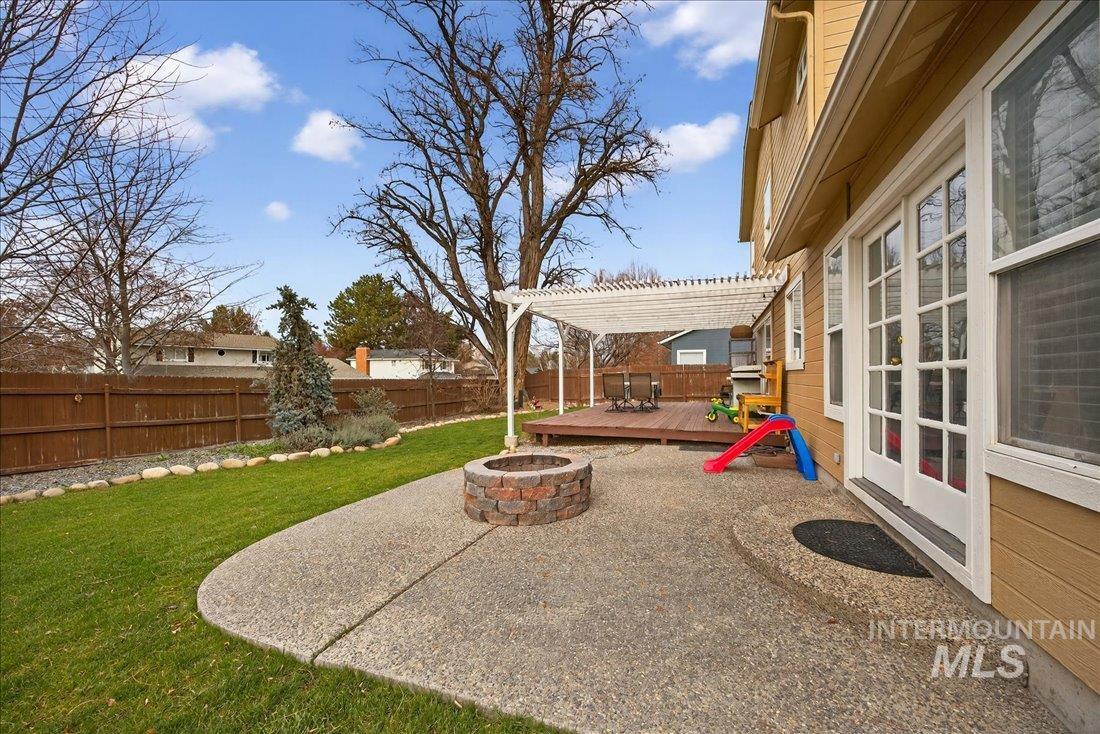 Fenced backyard featuring an outdoor fire pit and a deck