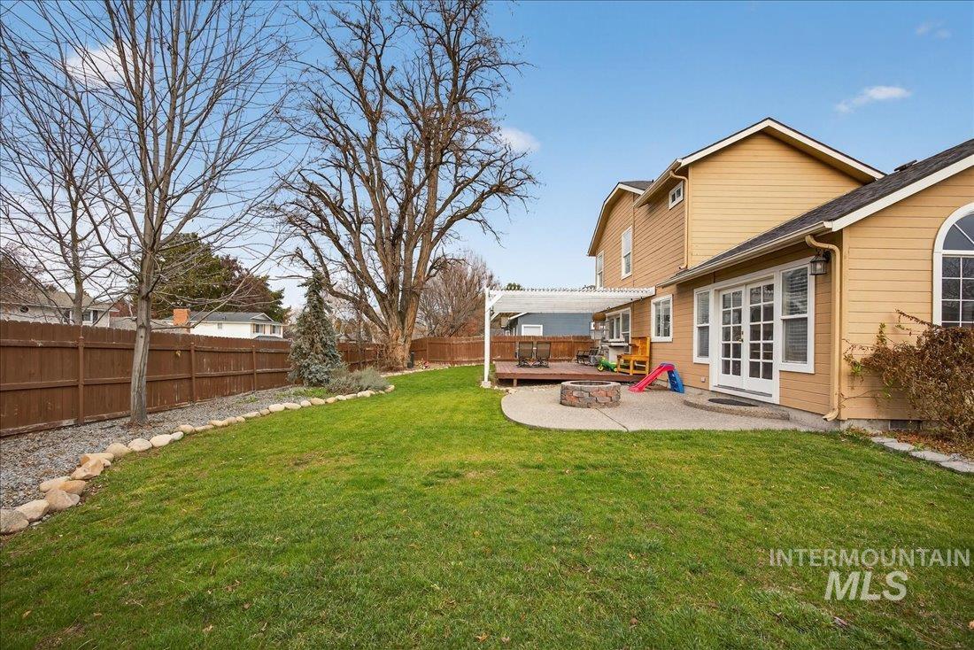 Fenced backyard featuring a deck, an outdoor fire pit, a pergola, a patio, and french doors