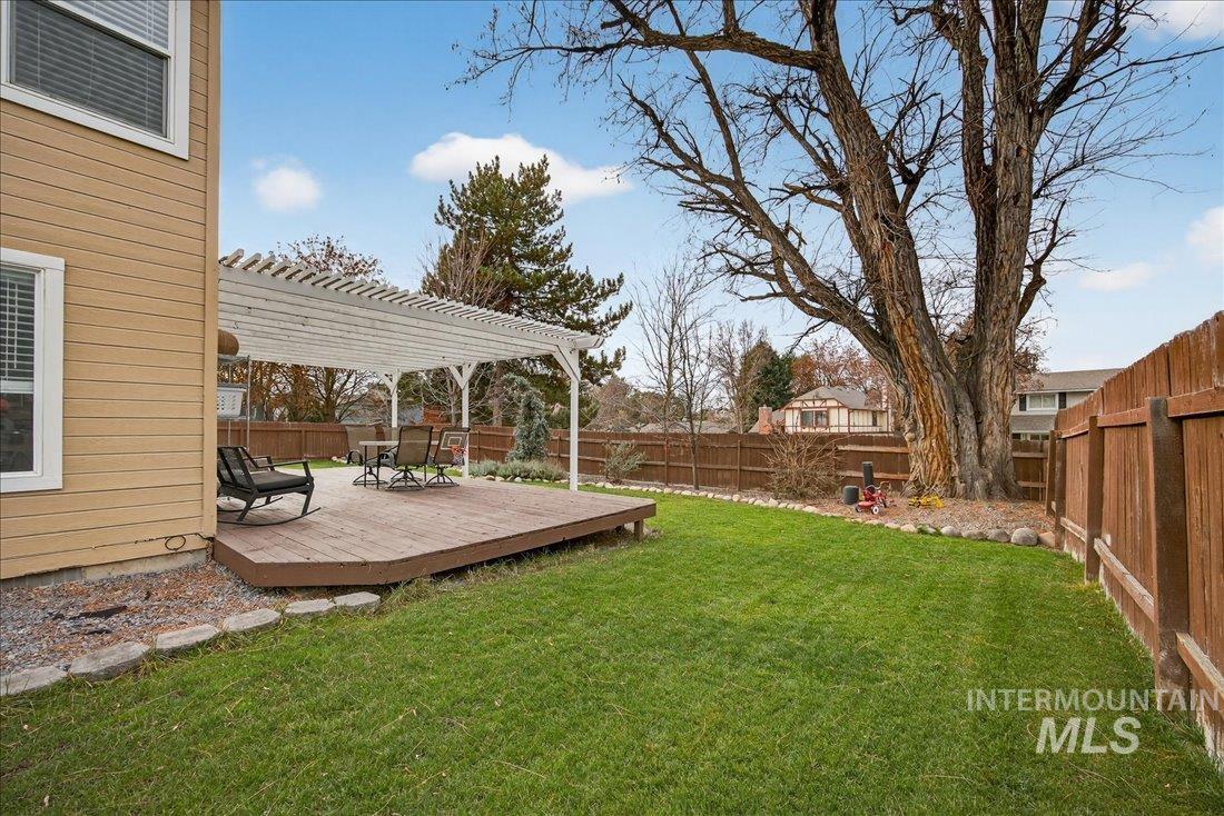 Fenced backyard featuring a wooden deck and a pergola