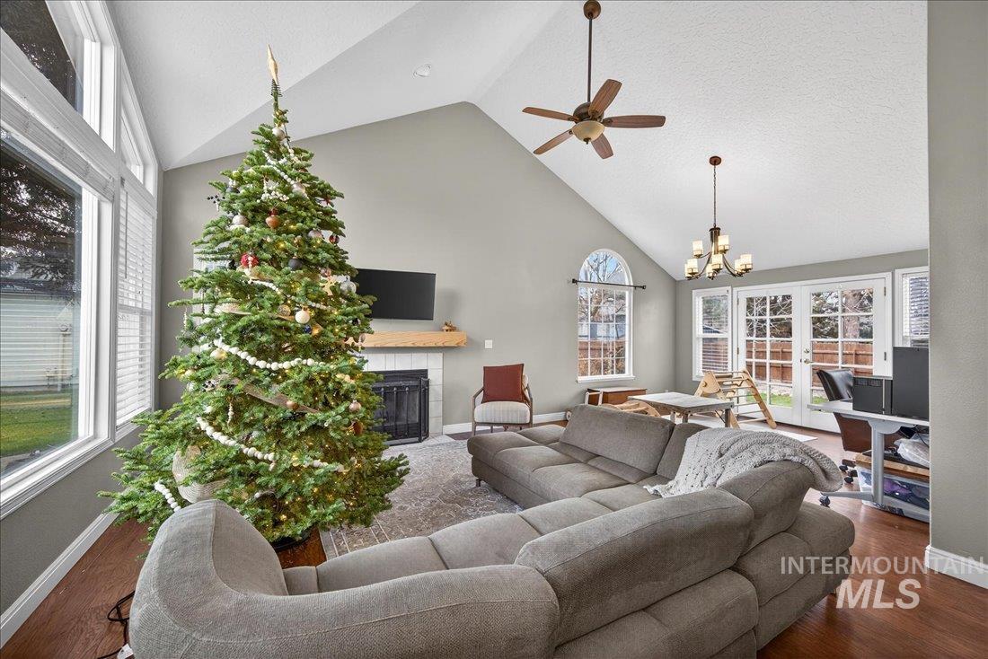 Living area featuring a fireplace, wood finished floors, high vaulted ceiling, a chandelier, and a textured ceiling