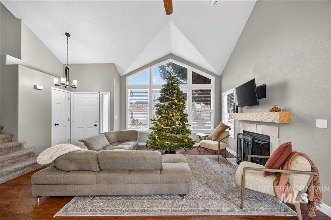 Living room with a fireplace, wood finished floors, high vaulted ceiling, and a chandelier