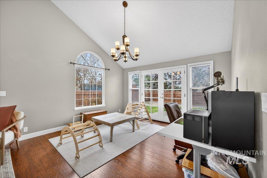Dining room with french doors, a desk, wood finished floors, high vaulted ceiling, and a chandelier