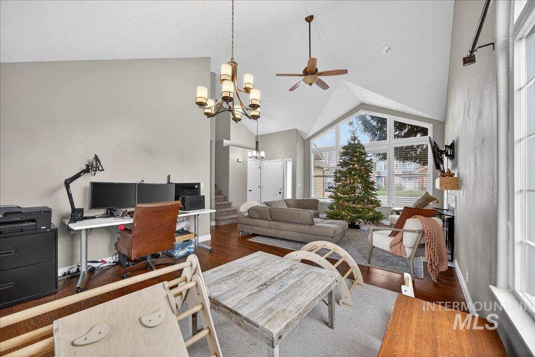 Home office featuring high vaulted ceiling, wood finished floors, a ceiling fan, and a chandelier