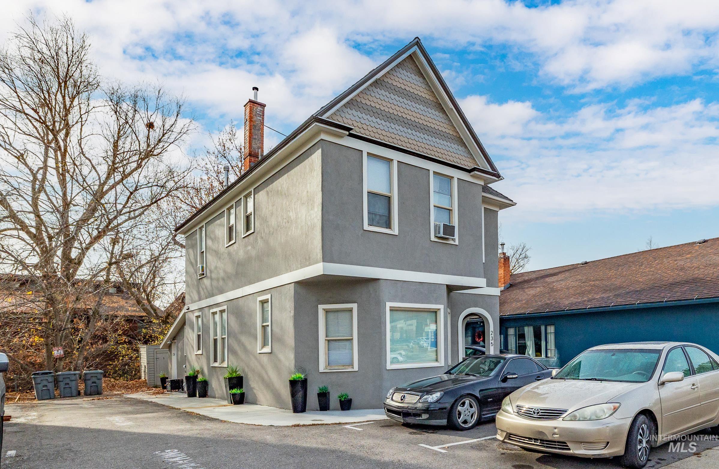 View of front facade with stucco siding, a chimney, and uncovered parking