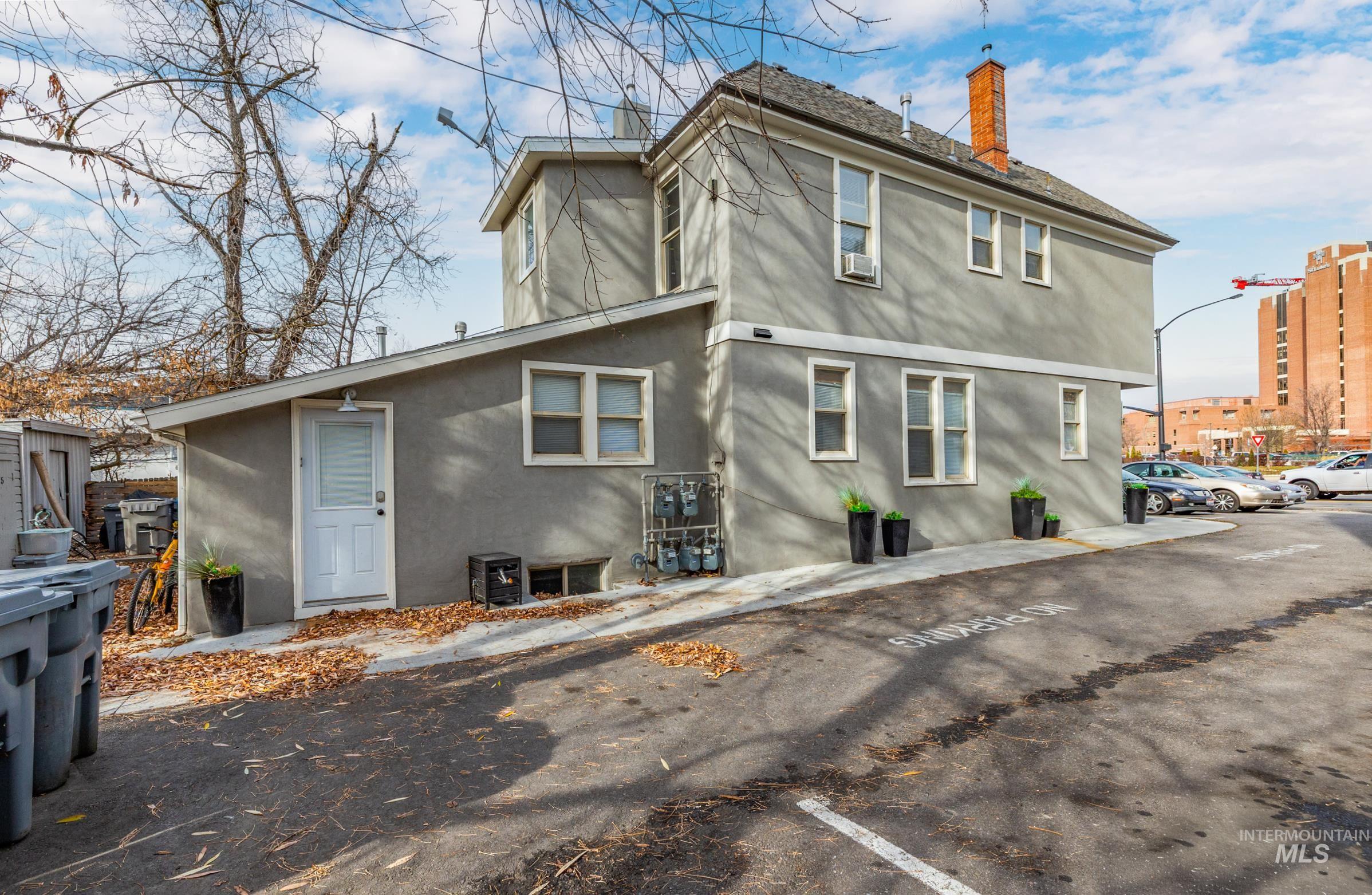 Rear view of property with stucco siding, a chimney, and uncovered parking