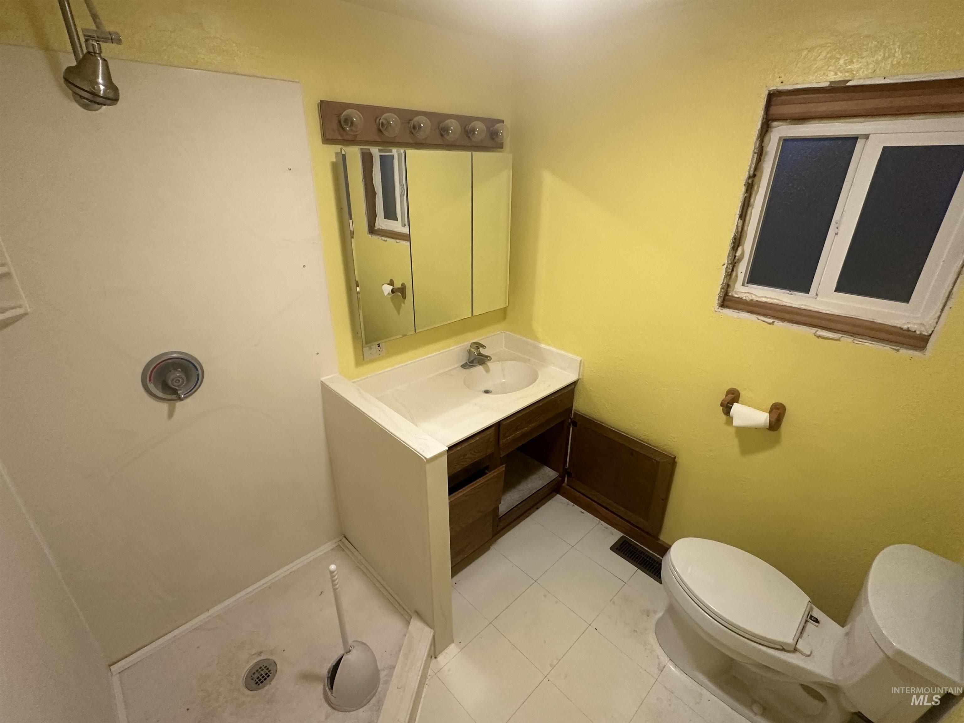 Full bath featuring vanity, a shower stall, light tile patterned flooring, and a textured wall