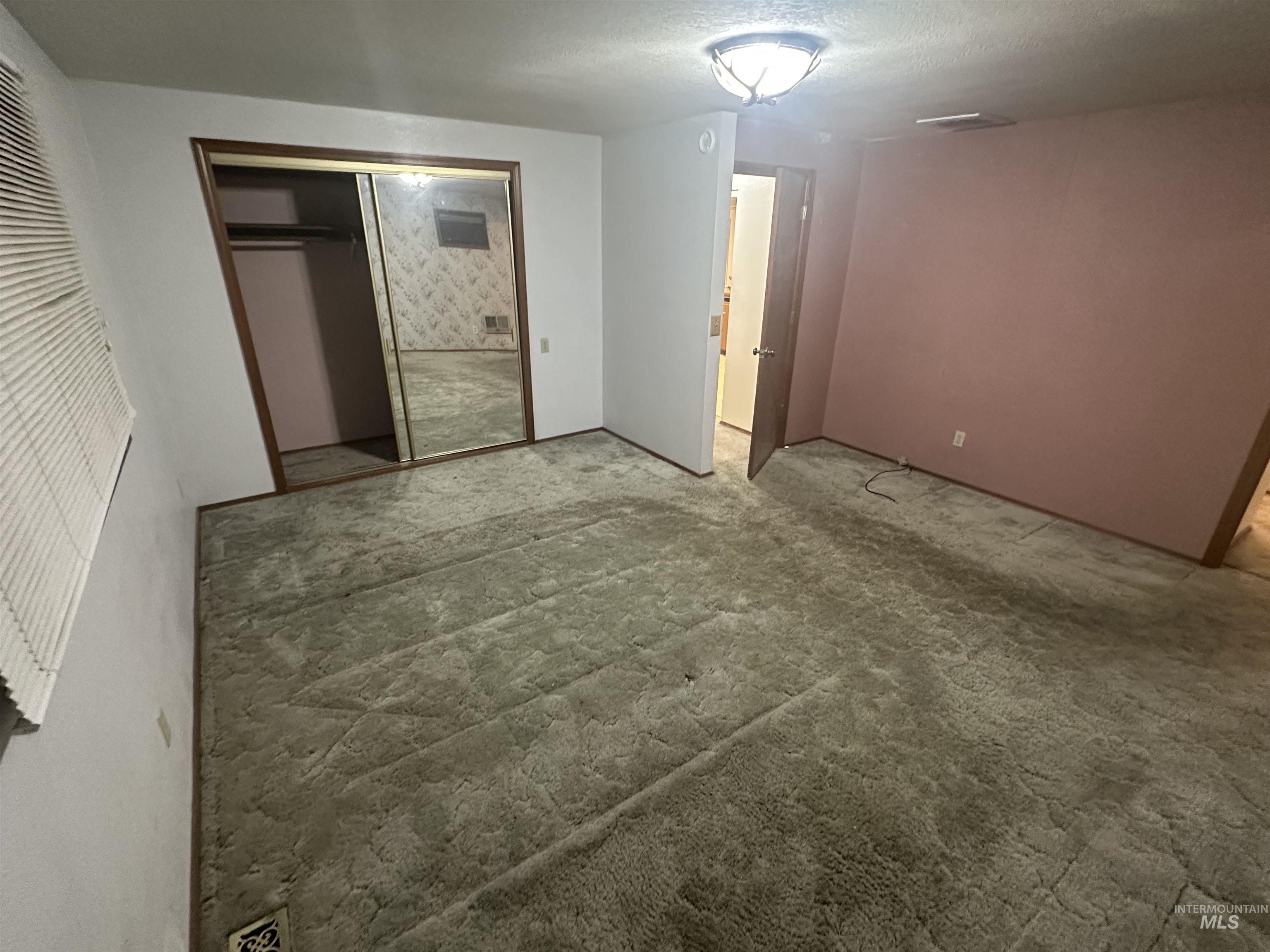 Unfurnished bedroom with a closet, a textured ceiling, and carpet