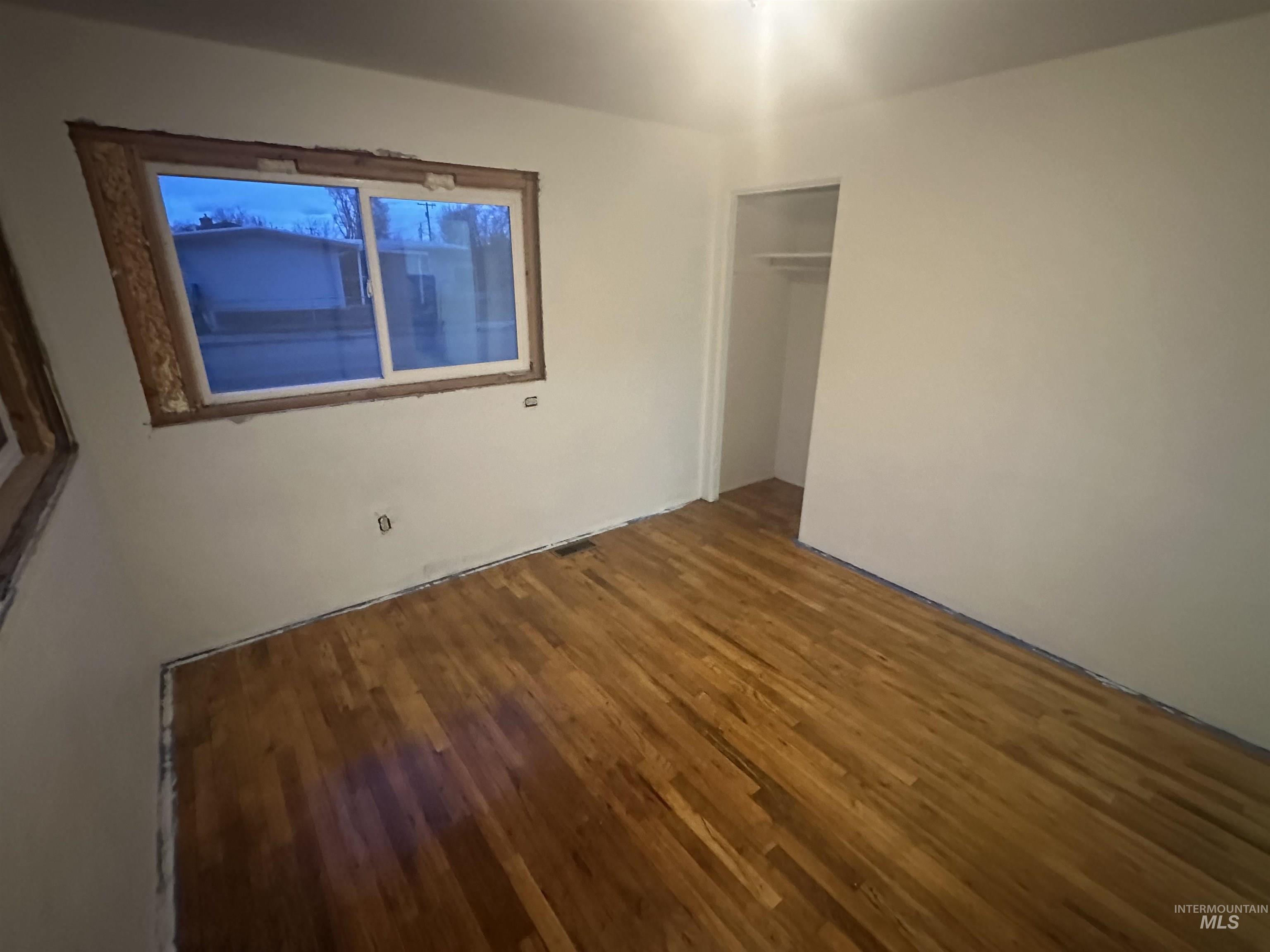 Unfurnished bedroom with wood finished floors and a closet