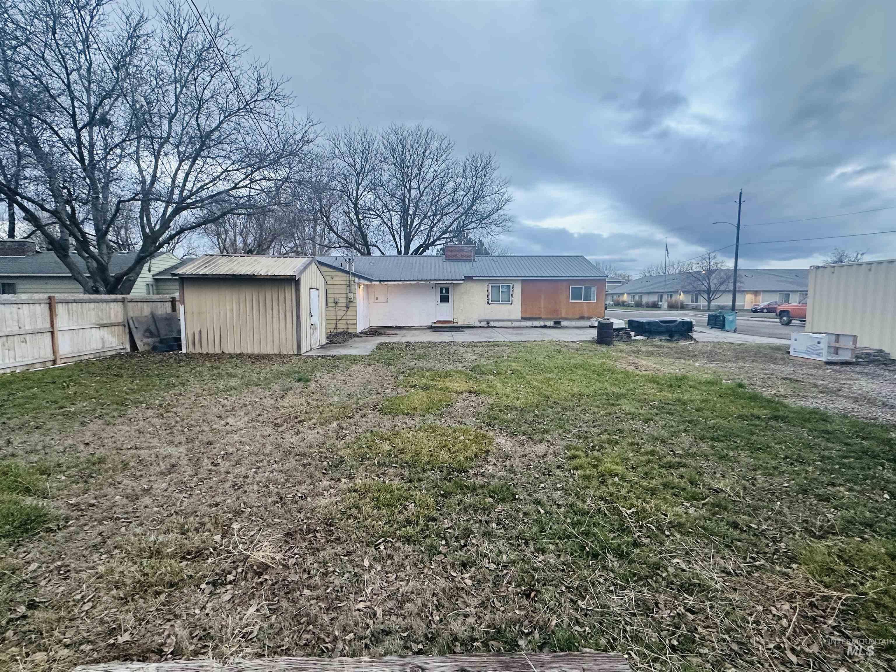 Rear view of property with a patio area, a chimney, a metal roof, and a shed