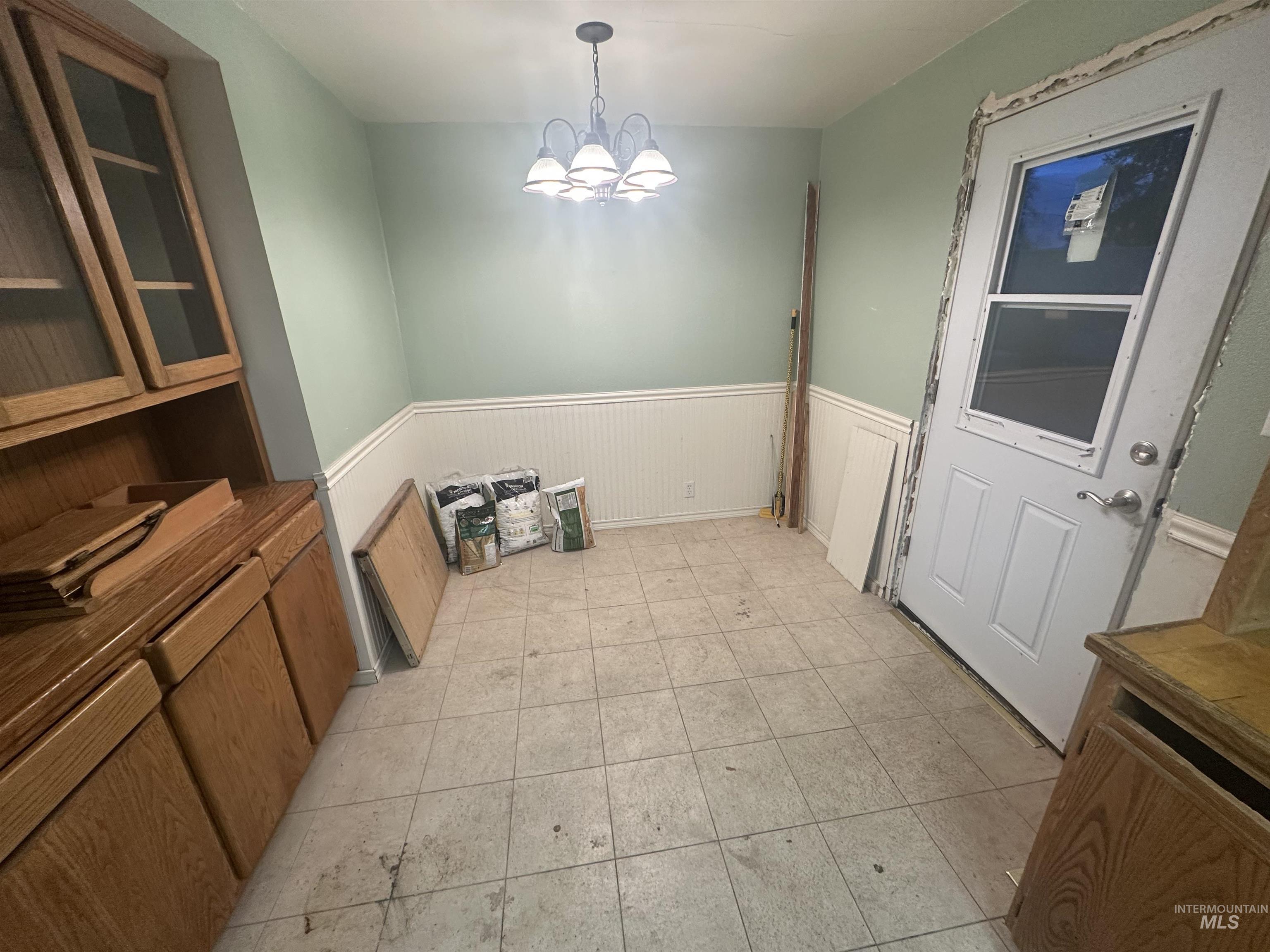 Unfurnished dining area with a wainscoted wall and a chandelier