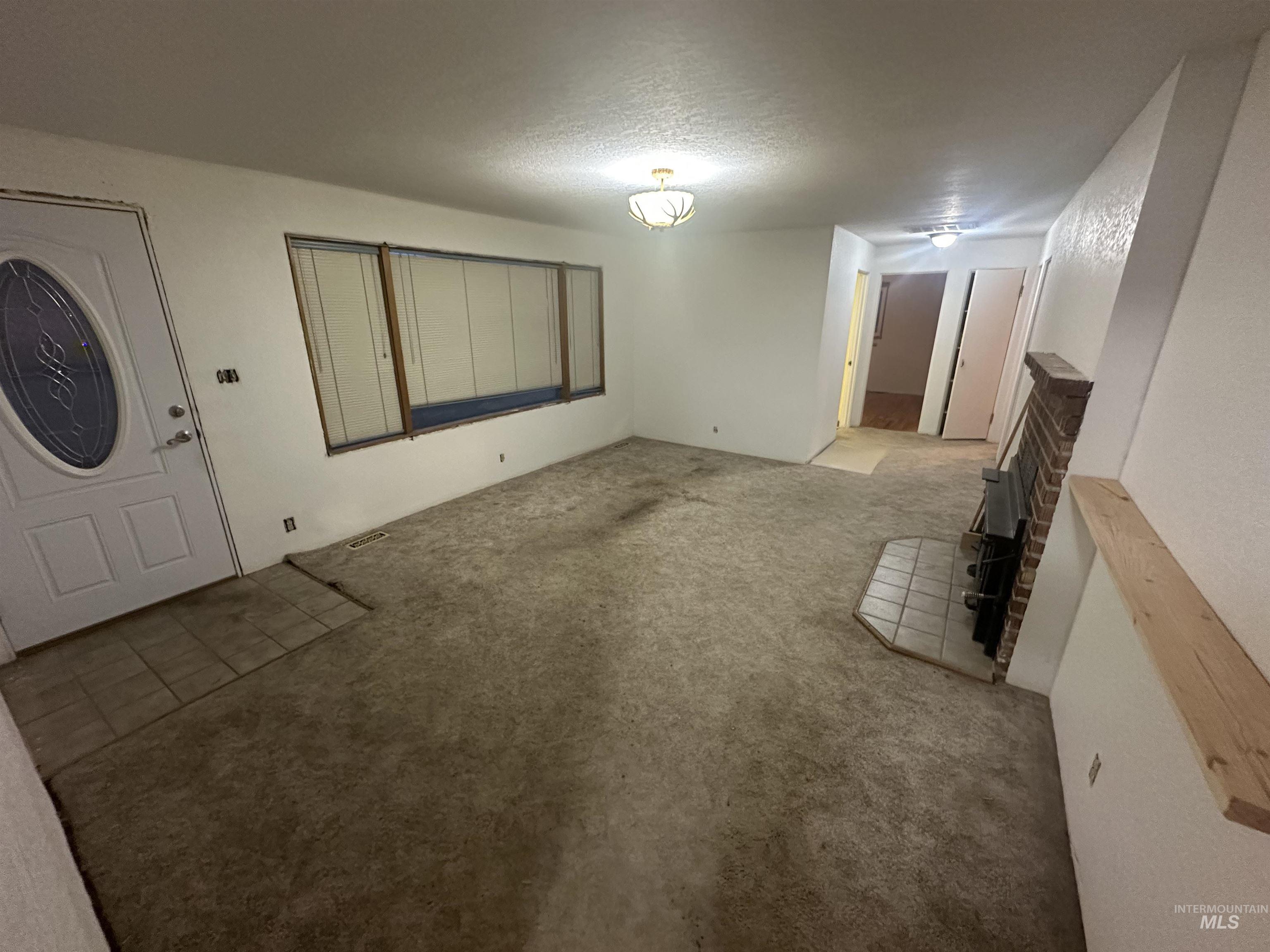 Unfurnished living room featuring carpet floors and a textured ceiling