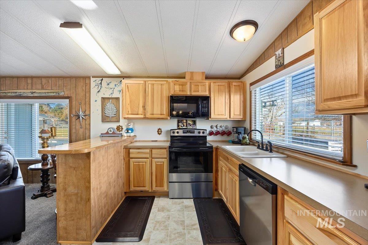 Kitchen featuring stainless steel appliances, light countertops, a peninsula, plenty of natural light, and a textured ceiling