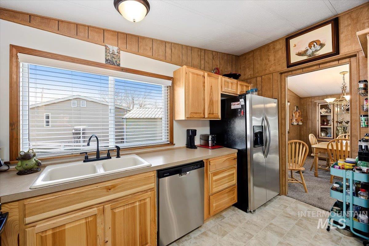 Kitchen featuring stainless steel appliances, wood walls, light countertops, and light brown cabinets