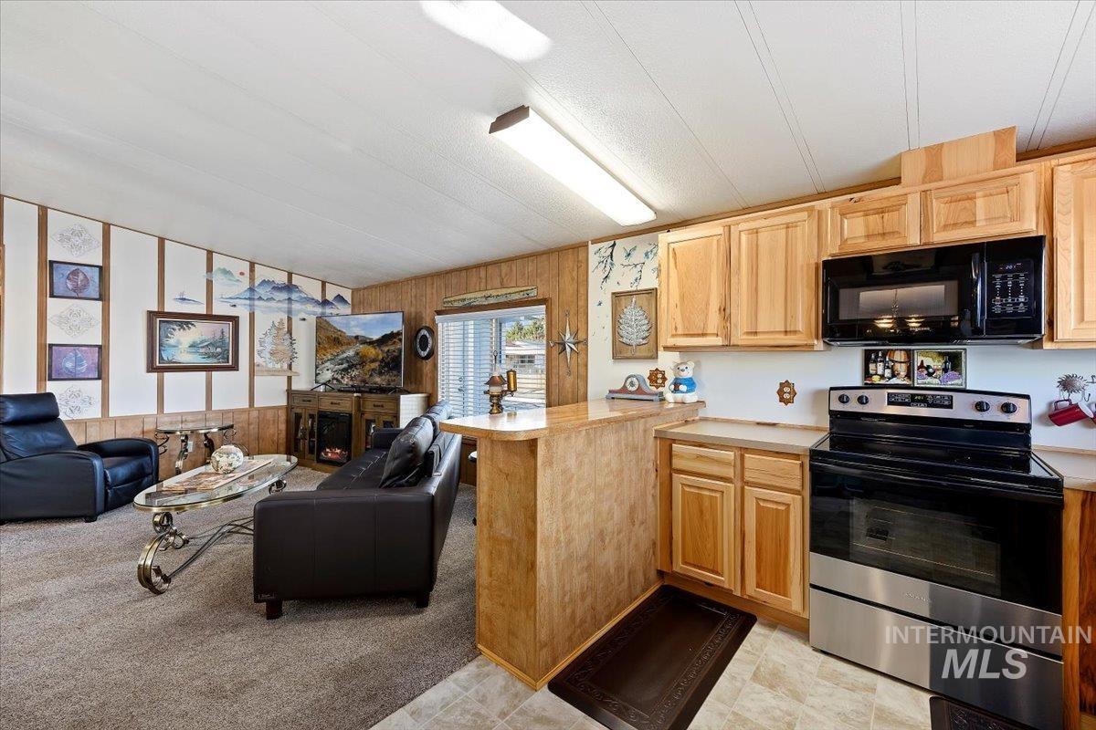 Kitchen with open floor plan, electric stove, light countertops, and wooden walls