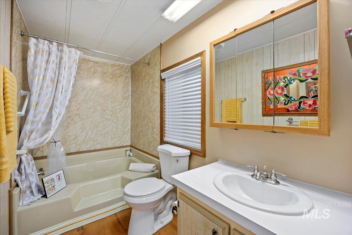 Full bathroom with shower / tub combo, vanity, and a textured ceiling