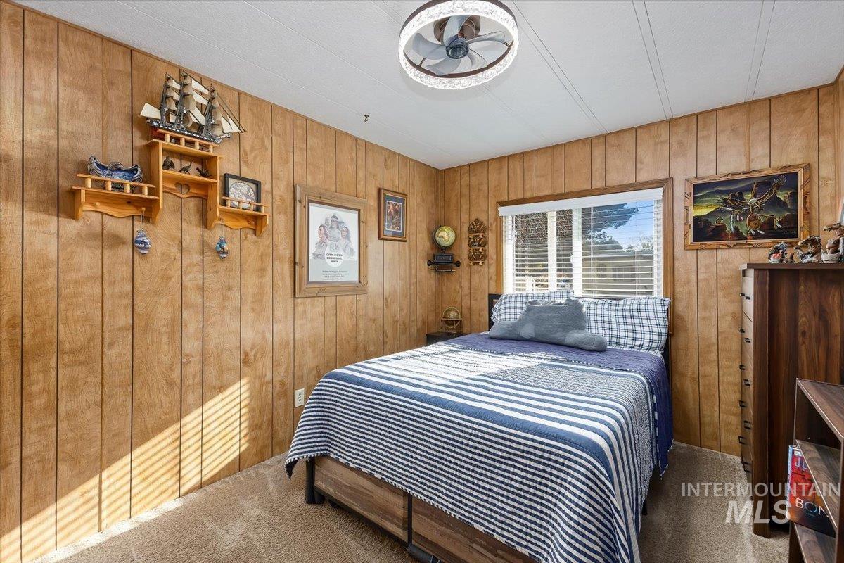 Carpeted bedroom with wood walls