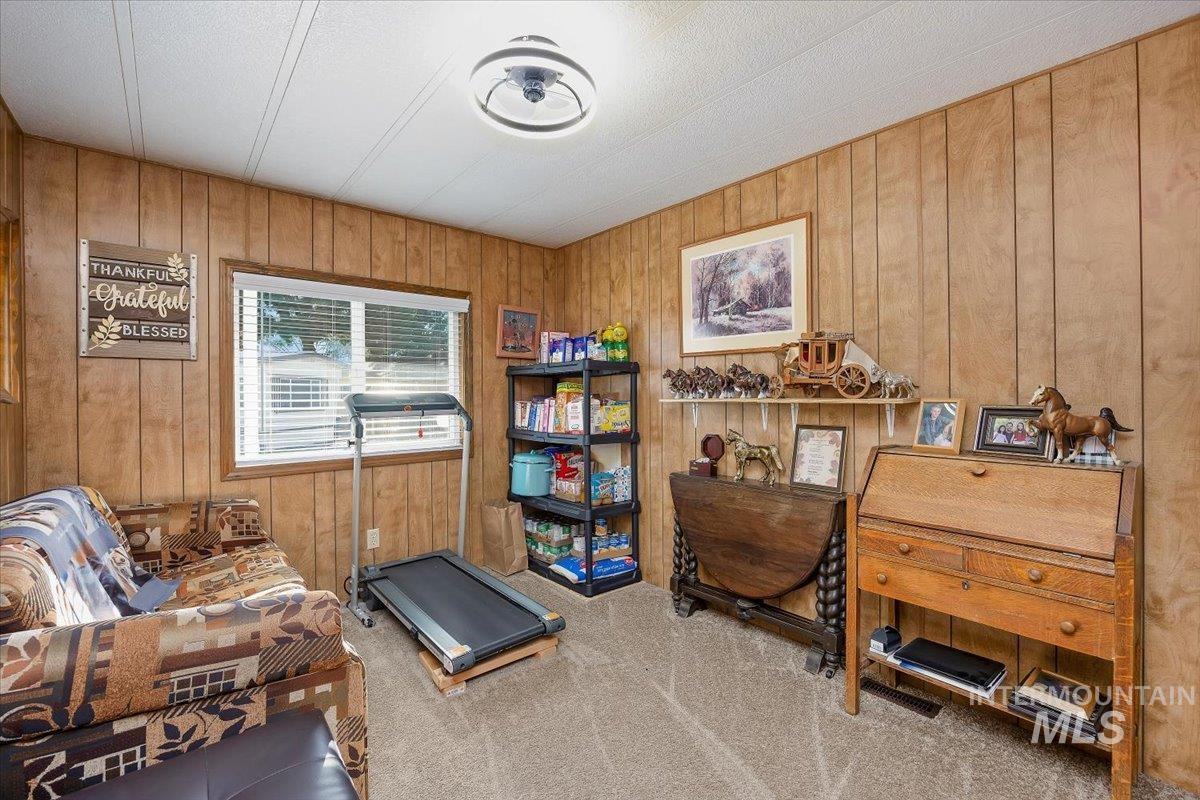 Carpeted office space featuring wood walls