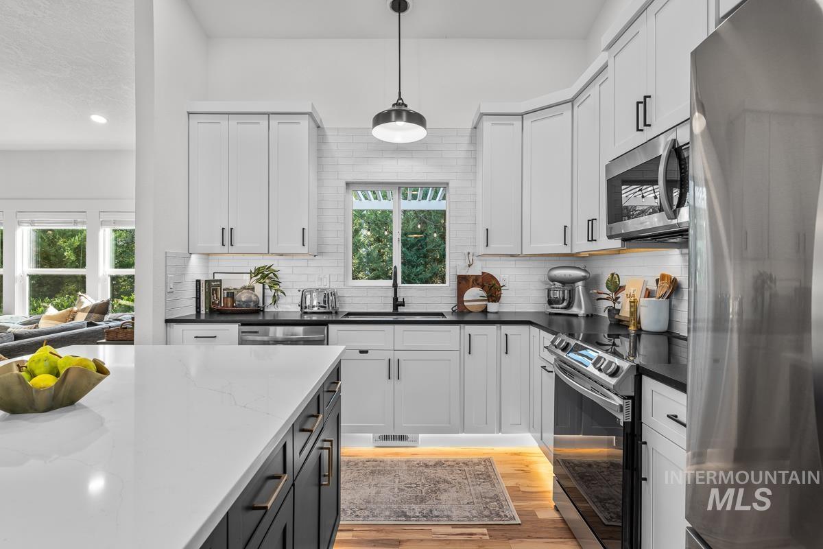 Kitchen featuring stainless steel appliances, decorative light fixtures, healthy amount of natural light, and dark stone counters