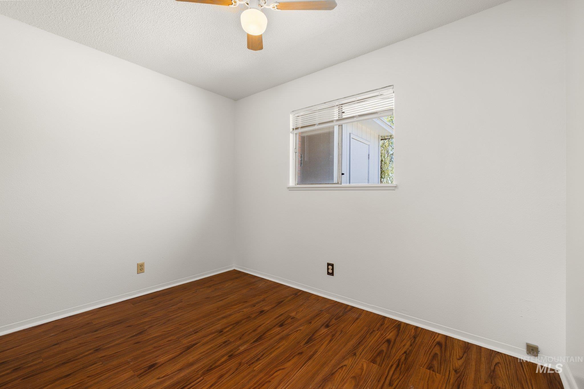 Spare room featuring dark wood-style flooring, a textured ceiling, and ceiling fan