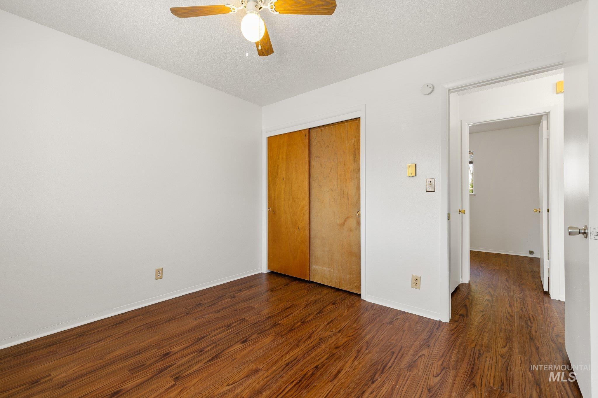 Unfurnished bedroom with dark wood-type flooring, a ceiling fan, and a closet