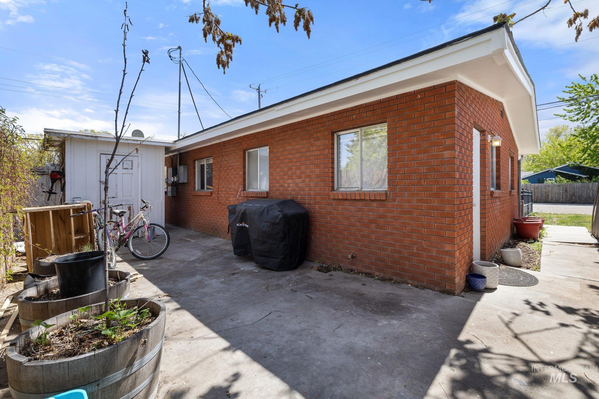 Back of property featuring brick siding, a patio area, and an outbuilding