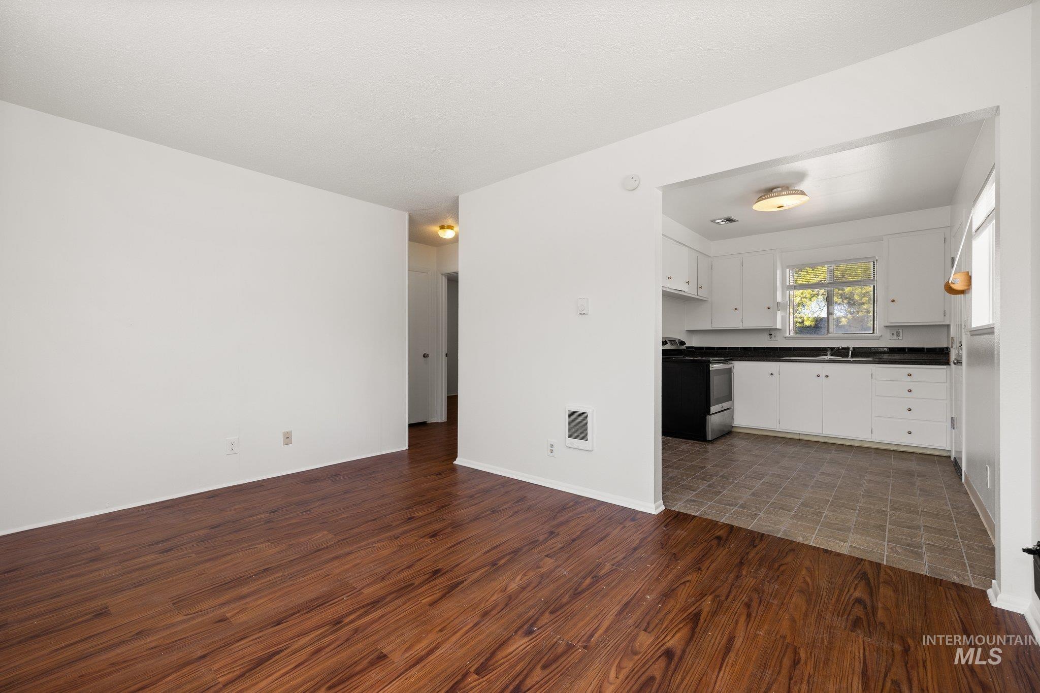 Unfurnished living room featuring dark wood finished floors