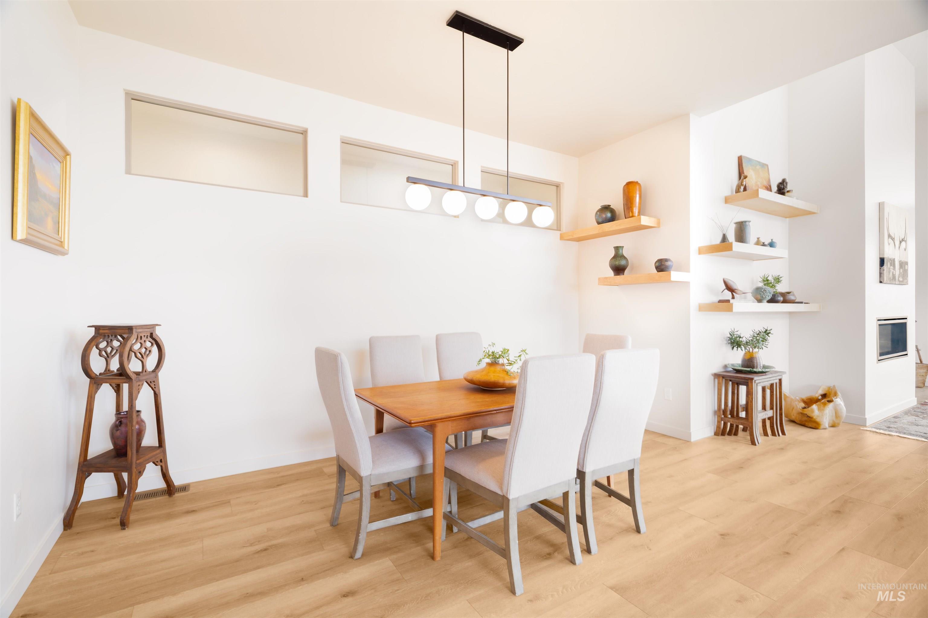 Dining area featuring light wood-style floors and a glass covered fireplace