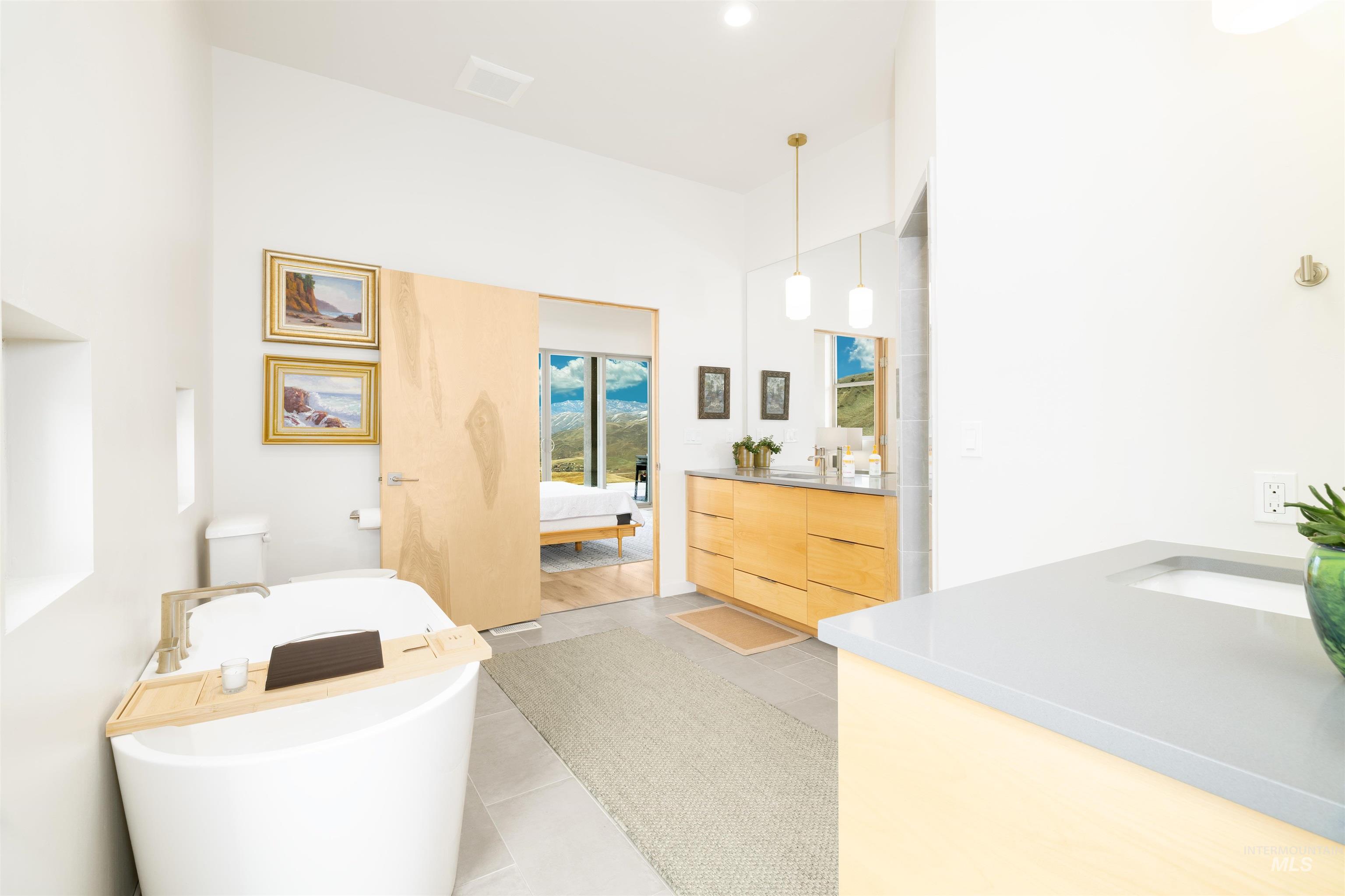 Ensuite bathroom with vanity, a freestanding tub, and light tile patterned flooring