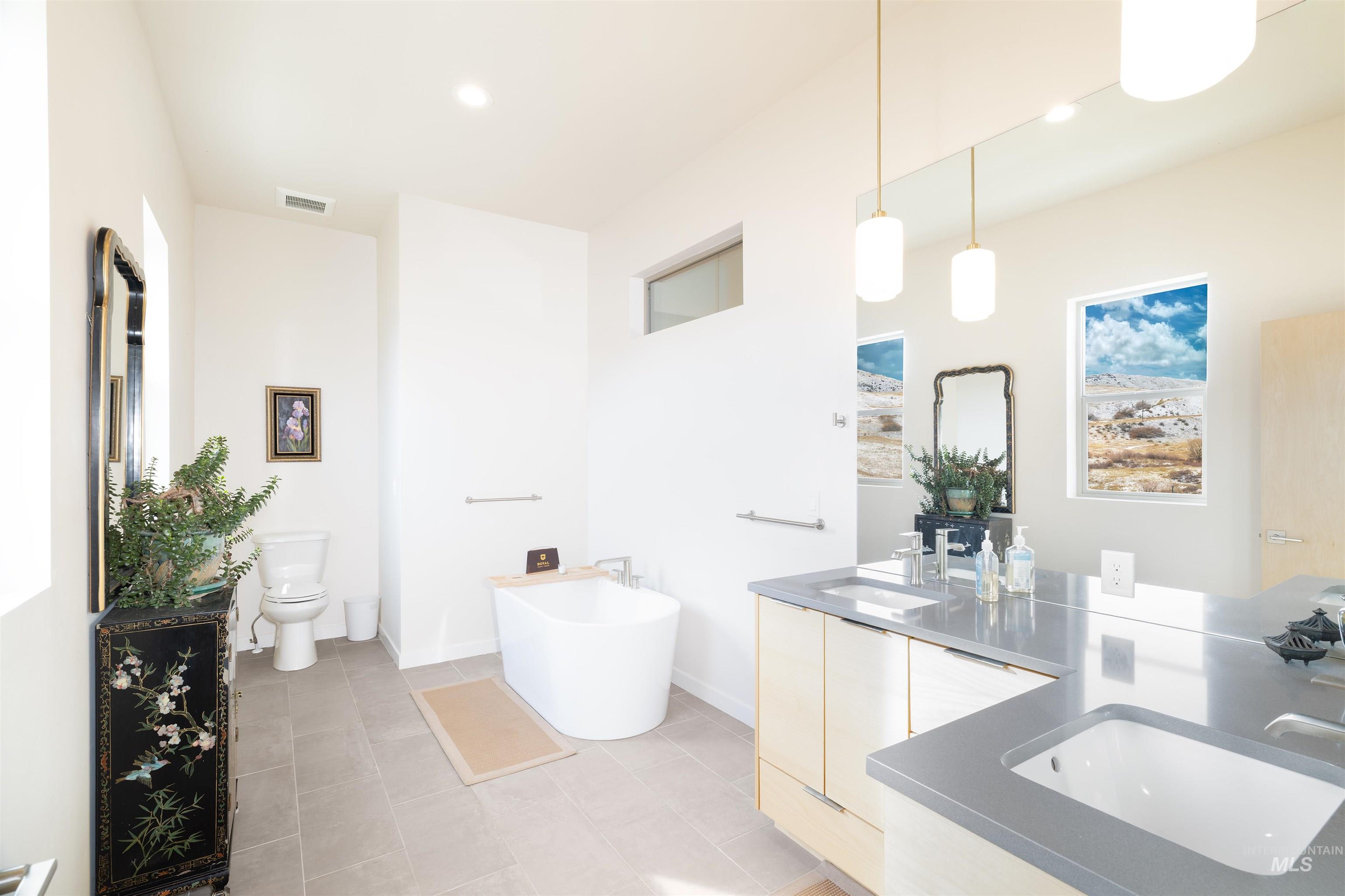 Bathroom with double vanity, a soaking tub, and light tile patterned floors