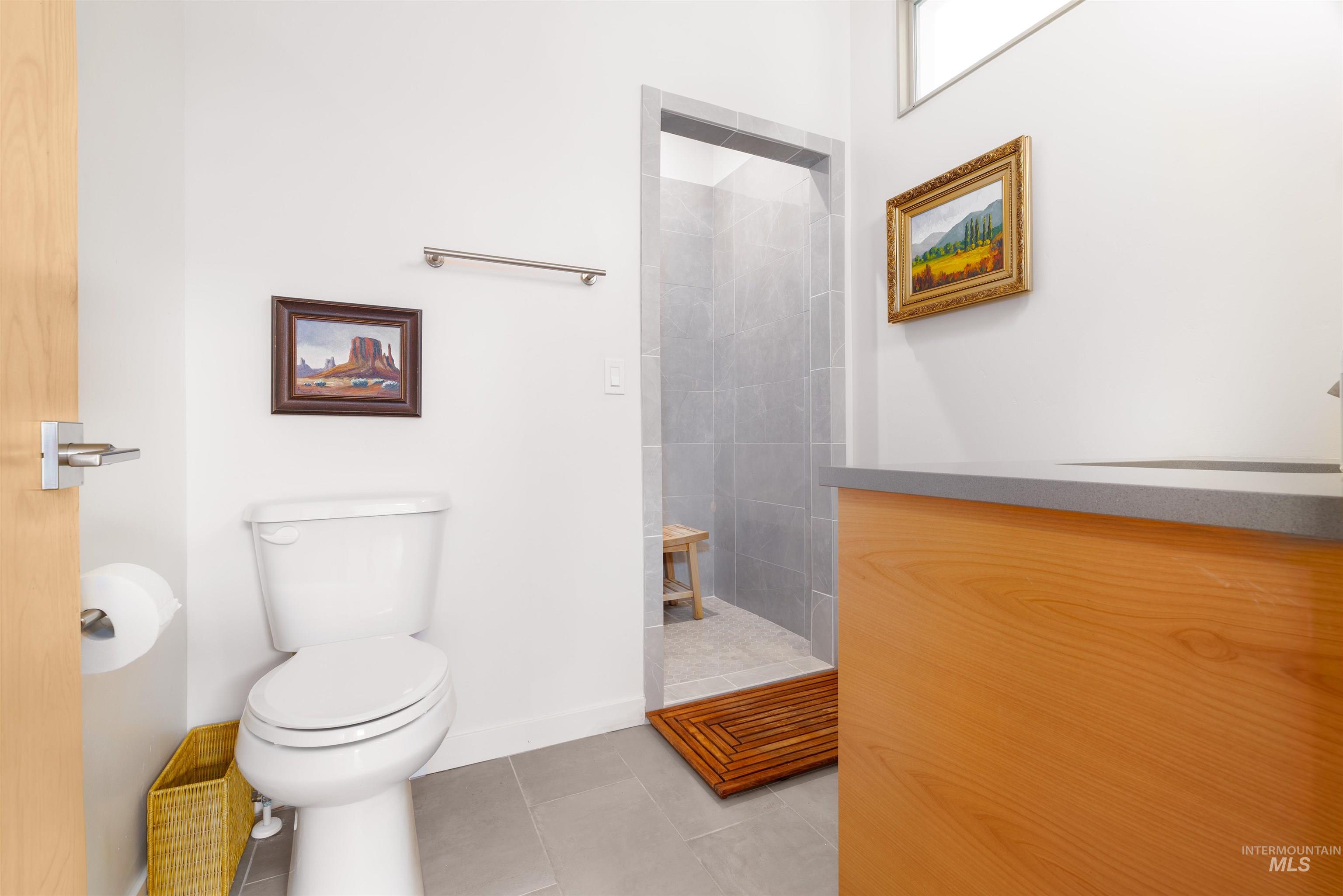 Bathroom with a tile shower, light tile patterned floors, and vanity