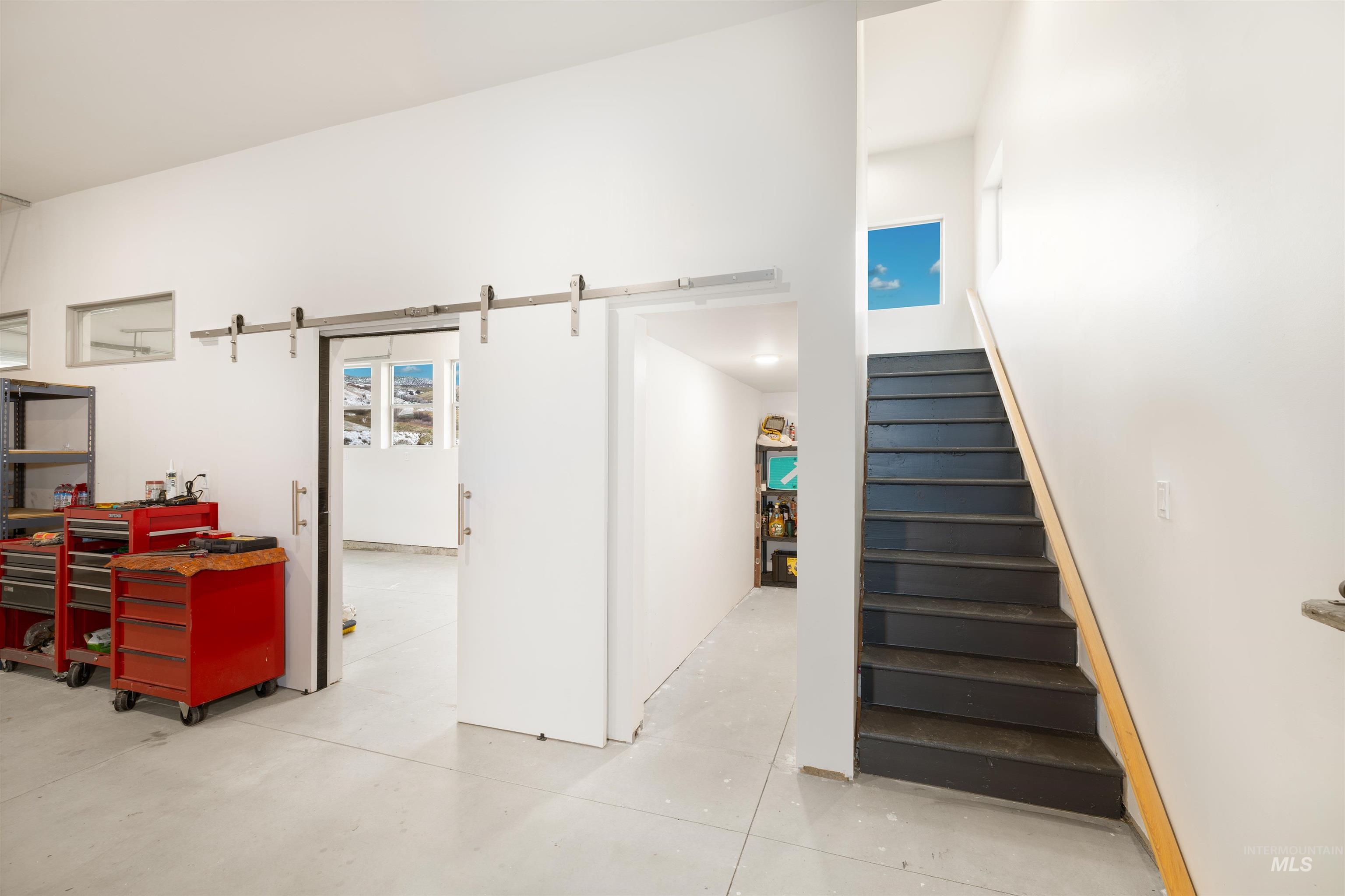 Stairs featuring concrete floors, a barn door, and a towering ceiling