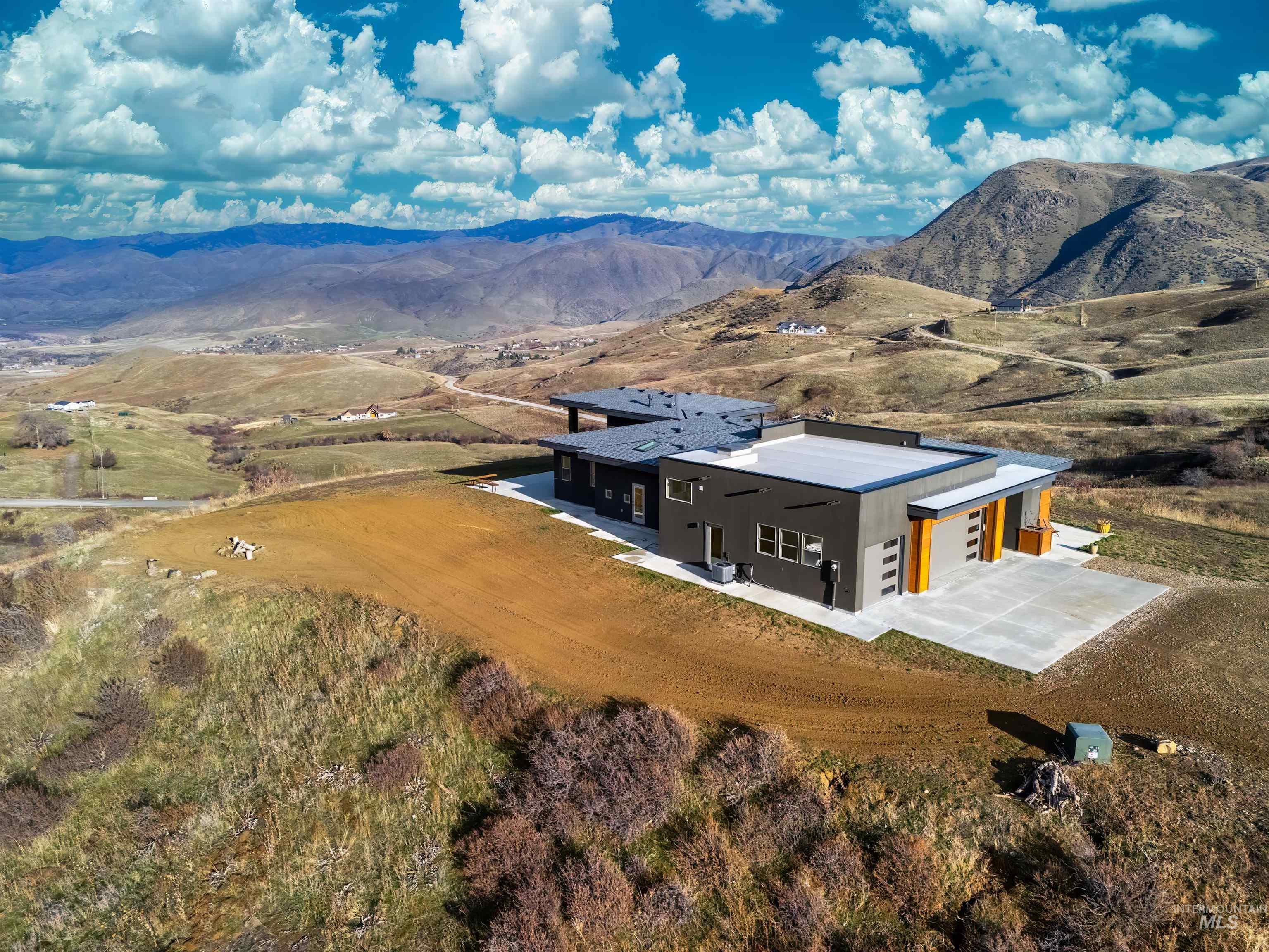 Aerial view of property and surrounding area featuring a mountain backdrop