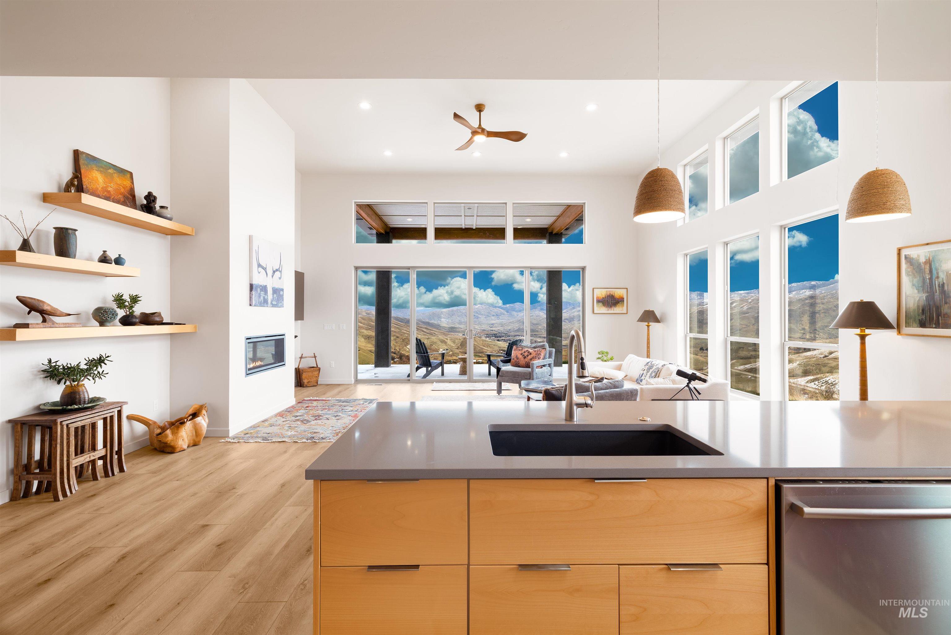 Kitchen featuring light brown cabinetry, open floor plan, stainless steel dishwasher, modern cabinets, and ceiling fan