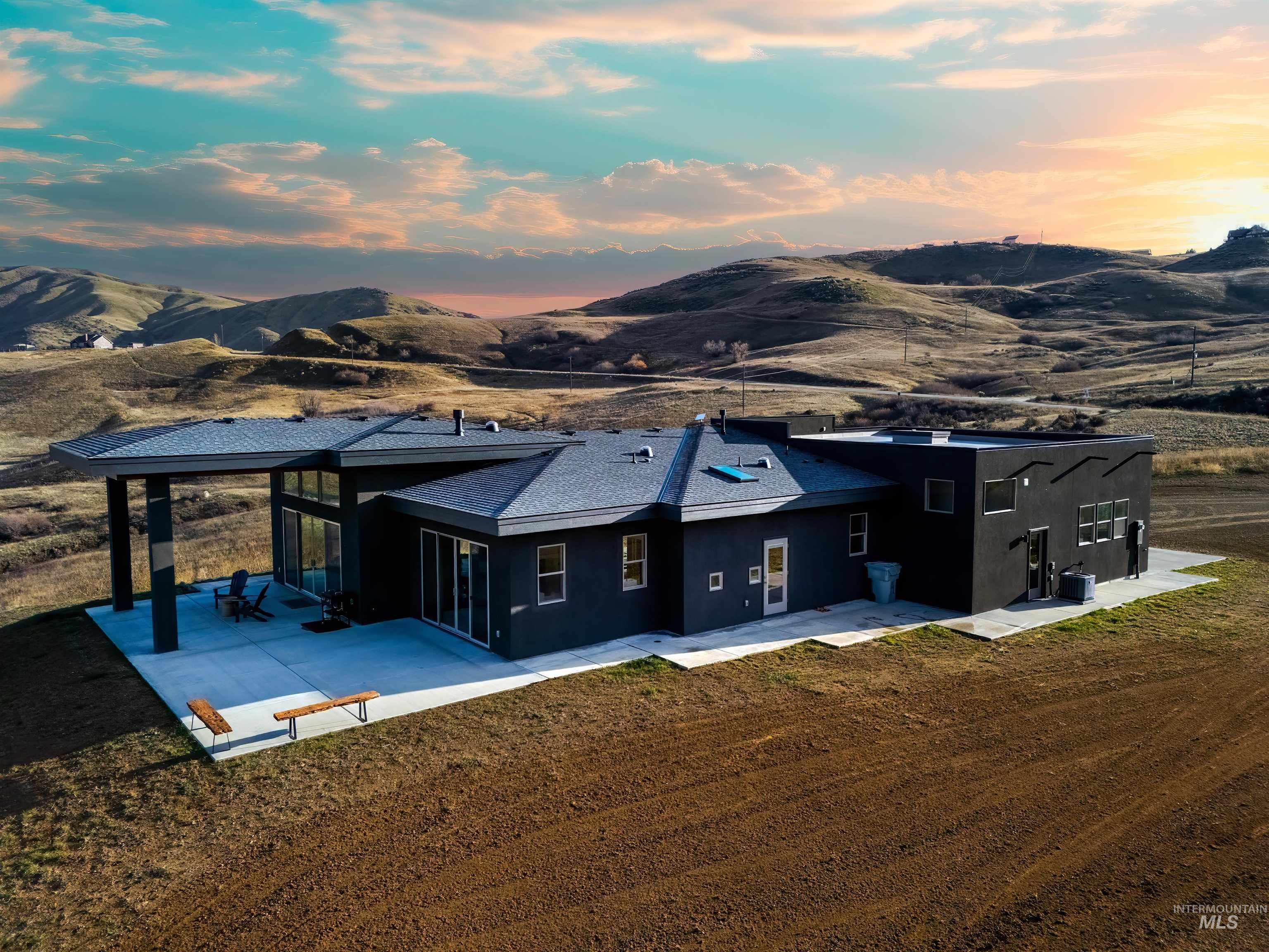 Back of house at dusk with stucco siding, a sunroom, a mountain view, and a patio