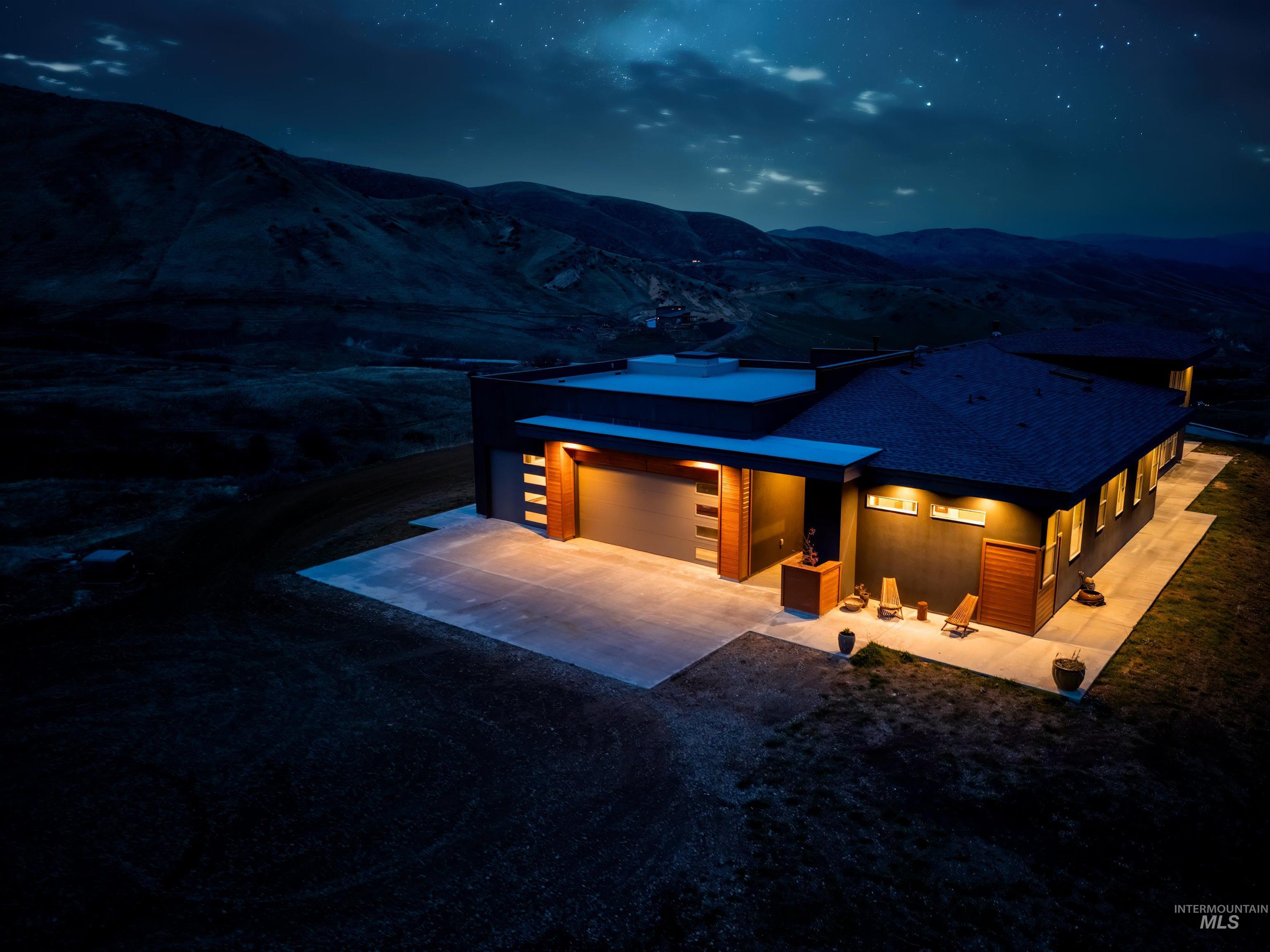 View of front of property featuring driveway, a patio area, and an attached garage
