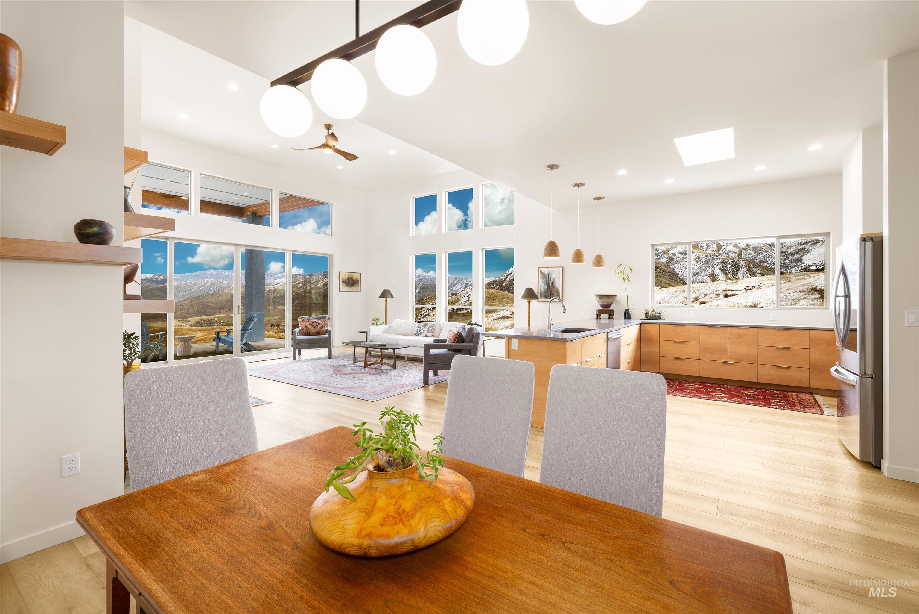 Dining area featuring light wood-style flooring, a skylight, and a towering ceiling