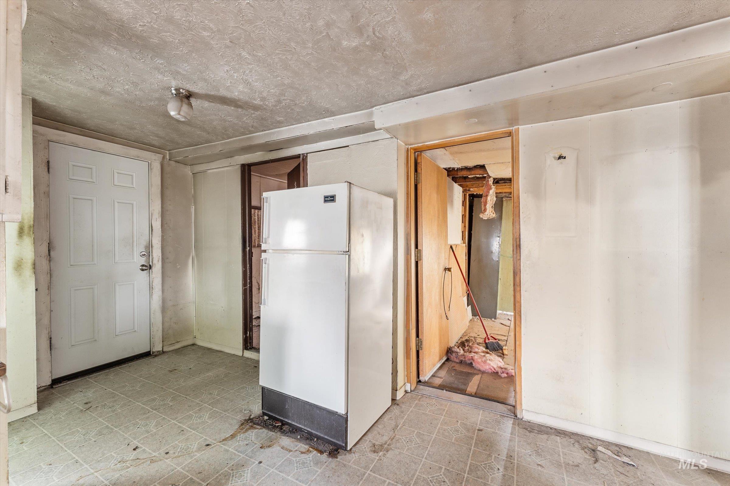 Kitchen with freestanding refrigerator, light flooring, and a textured ceiling