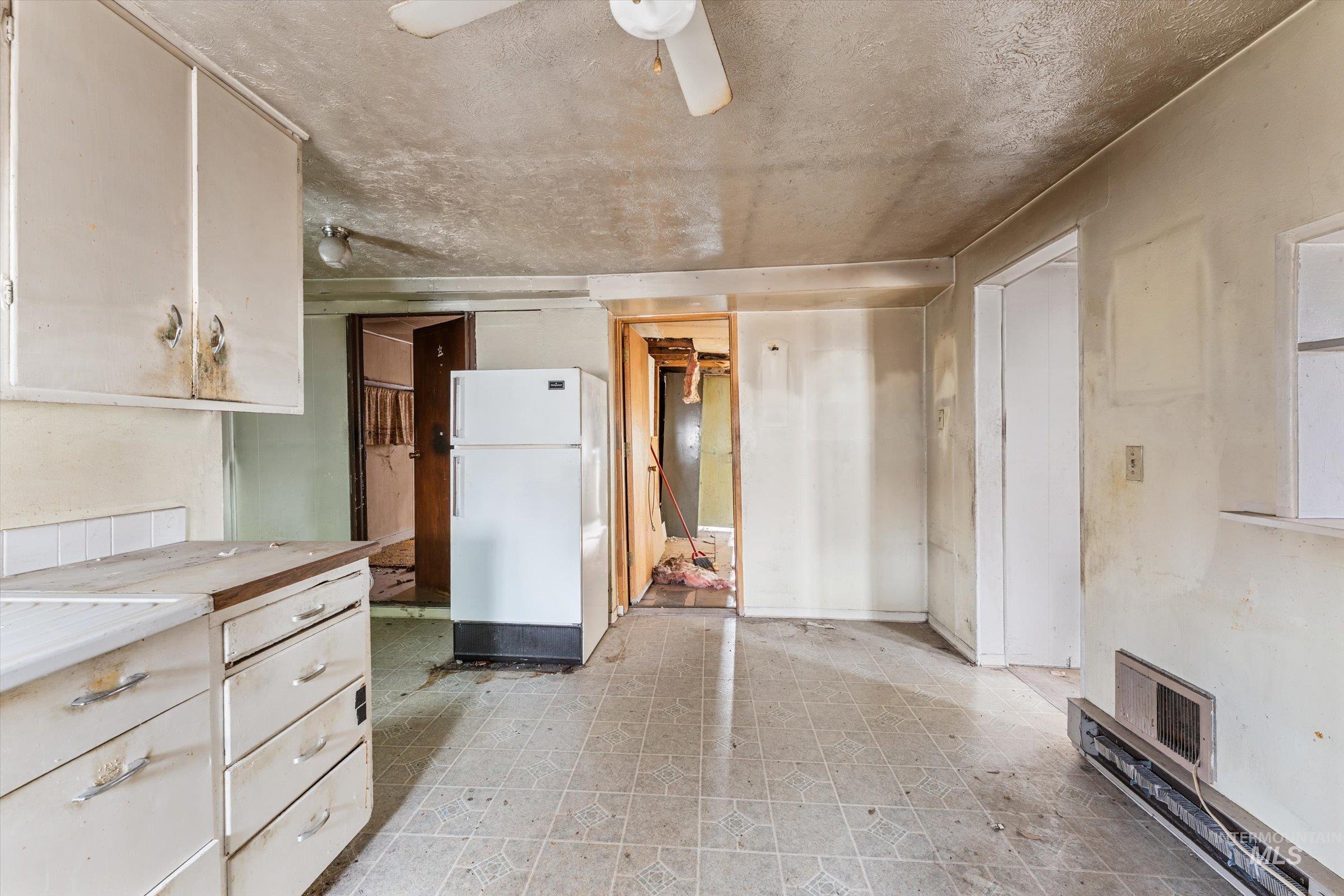 Kitchen with light flooring, freestanding refrigerator, and a textured ceiling