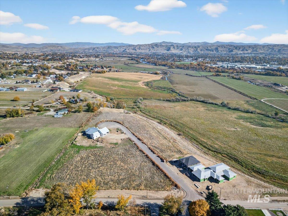 Aerial view of sparsely populated area with large plots for crops and a mountainous background