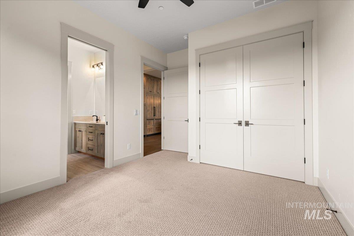 Unfurnished bedroom featuring light carpet, ceiling fan, connected bathroom, and a closet