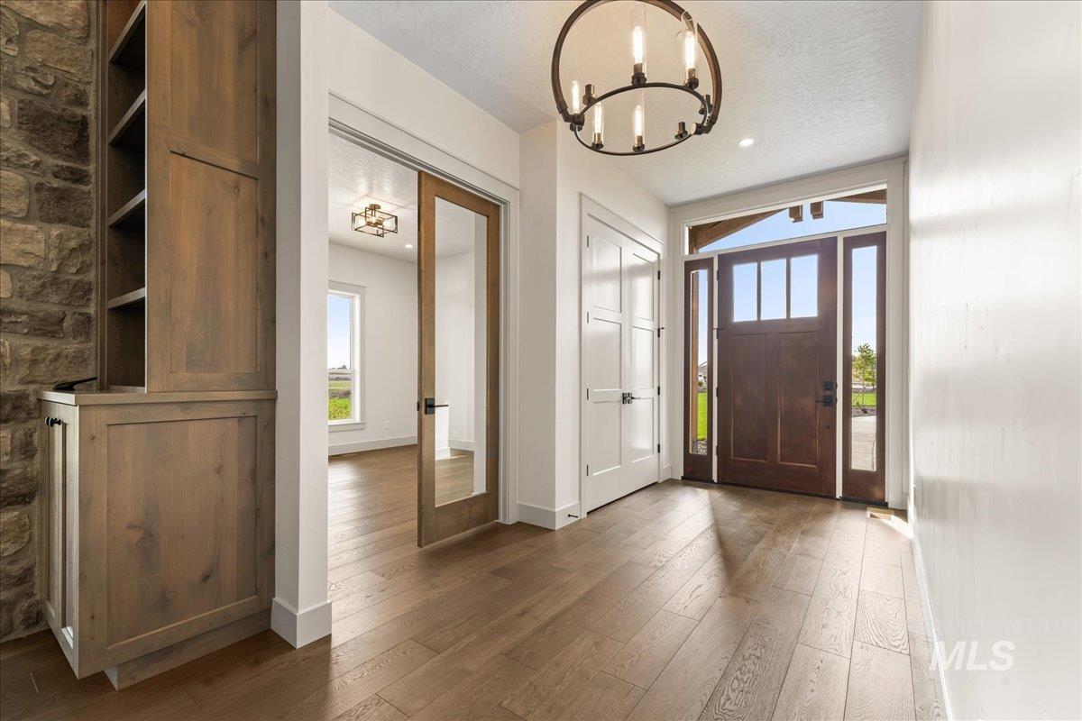 Foyer featuring healthy amount of natural light, dark wood finished floors, a textured ceiling, and a chandelier